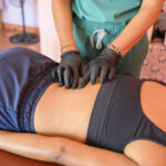 Profissional fazendo massagem nas costas de um paciente.