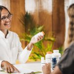 Cliente conversando com vendedora olhando produtos na bancada com um sorriso no rosto