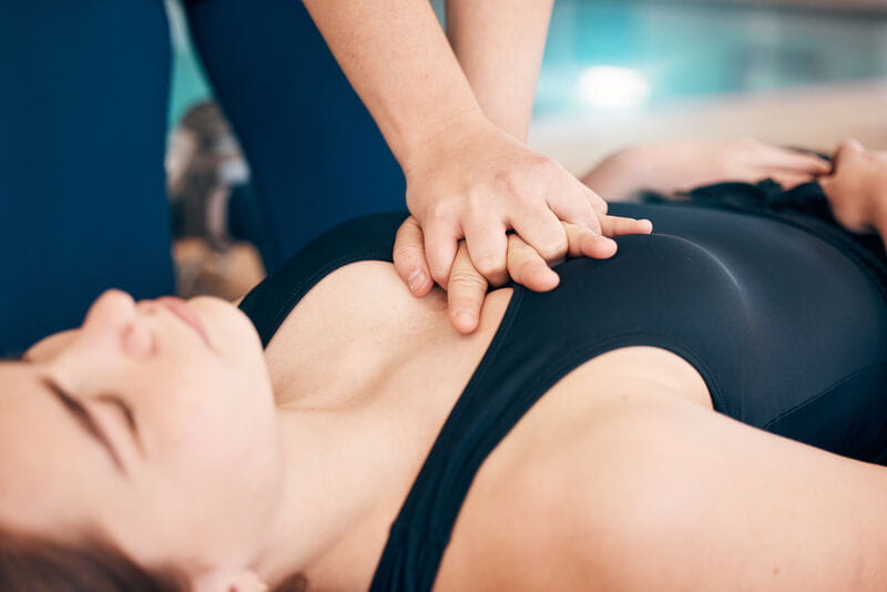 Mulher deitada ao chão recebendo massagem cardiaca