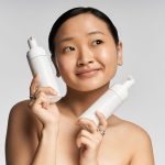 Modelo segurando frascos de produtos de beleza